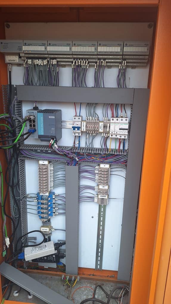 Control panel with automation modules, power supply, terminal blocks and wiring inside an orange enclosure
