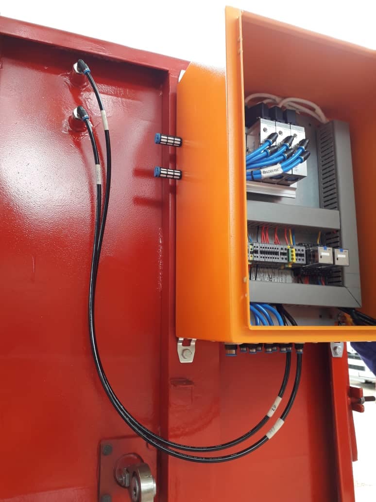 Open orange electrical cabinet with cables routed to the door-mounted controls