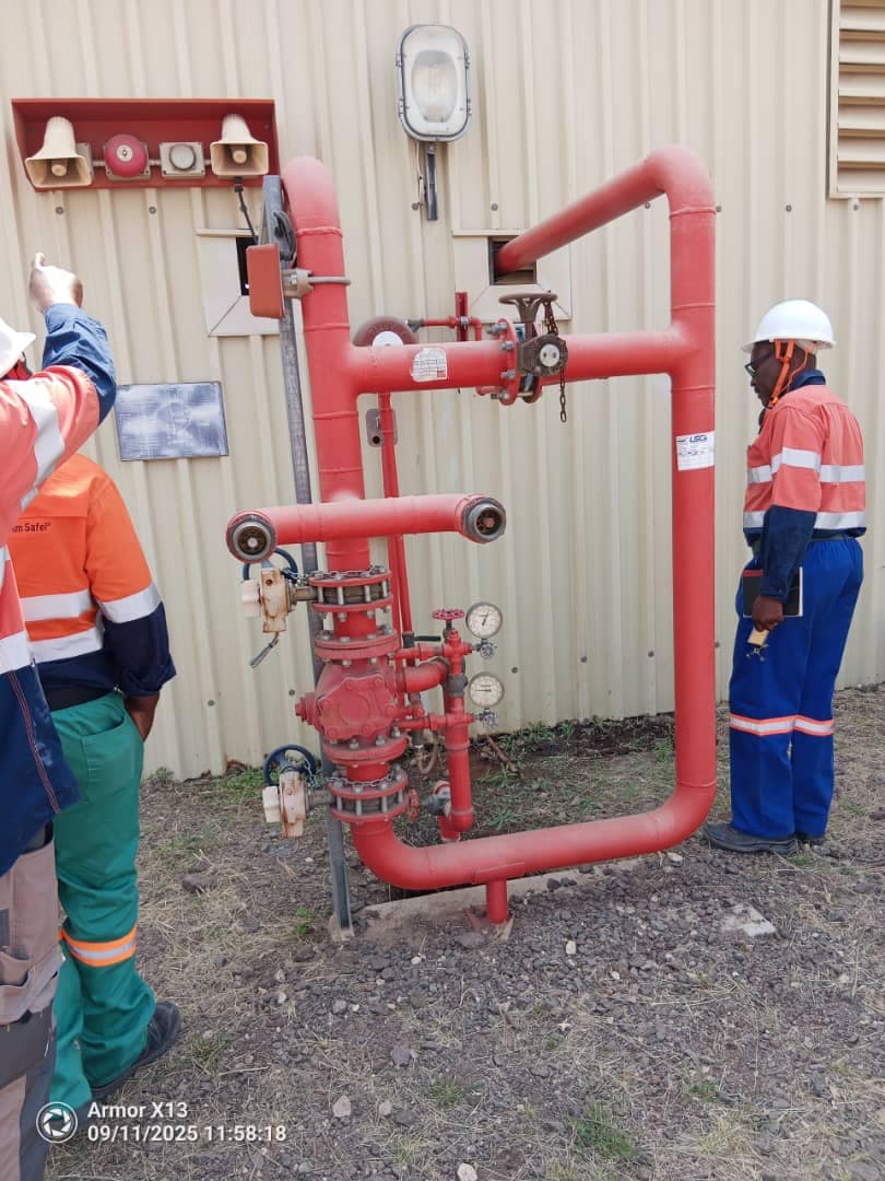 Bow Out team members beside red industrial pipework